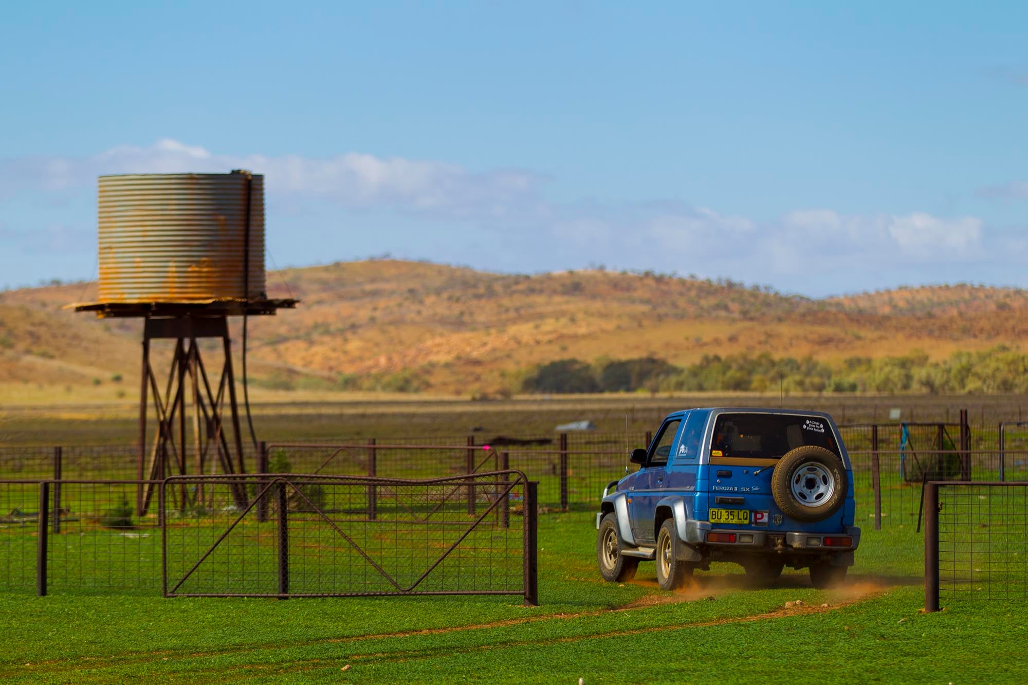 A four-wheel-drive vehicle beside a water tank with the ranges behind